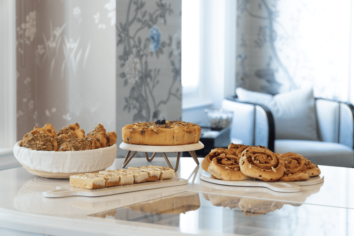 An assortment of baked goods, including cinnamon rolls, a tart on a stand, and sliced pastries.