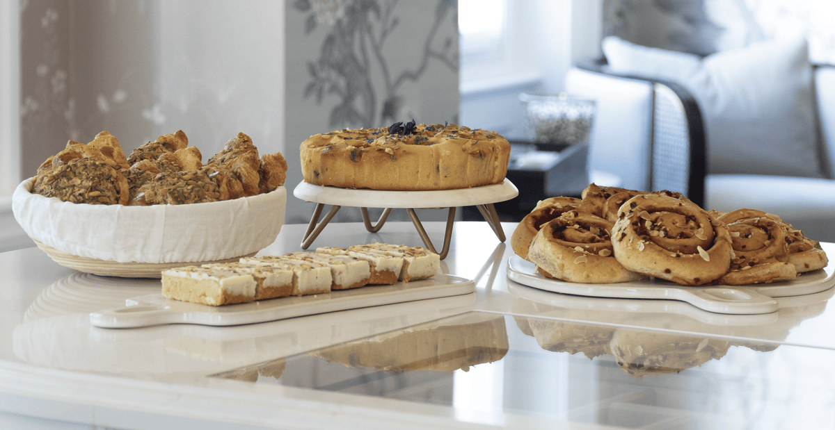 An assortment of baked goods displayed on a glossy white table in a bright, modern kitchen or dining area. 